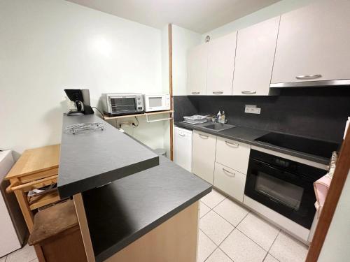 une cuisine avec des armoires blanches et un comptoir noir dans l'établissement Appartement confortable aux Sables-d'Olonne de 61 m², à Les Sables-dʼOlonne