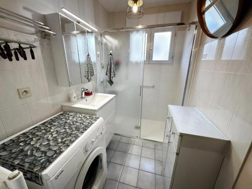 une salle de bain blanche avec une machine à laver et un lavabo dans l'établissement Appartement confortable aux Sables-d'Olonne de 61 m², à Les Sables-dʼOlonne