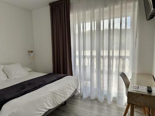 a bedroom with a bed and a desk and a window at Hotel SanMar in Cóbreces
