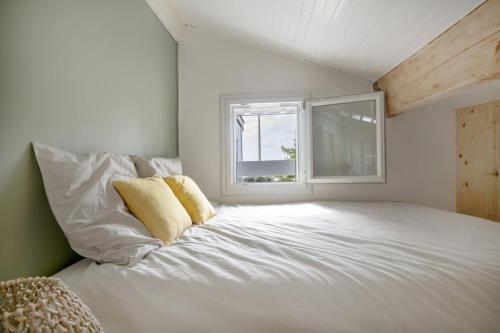 un lit blanc dans une chambre avec une fenêtre dans l'établissement Jolie maison face à l'océan Biscarrosse Plage, à Biscarrosse