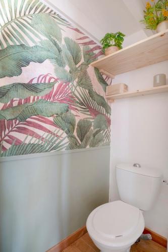 une salle de bain avec toilettes et un papier peint tropical dans l'établissement Jolie maison face à l'océan Biscarrosse Plage, à Biscarrosse