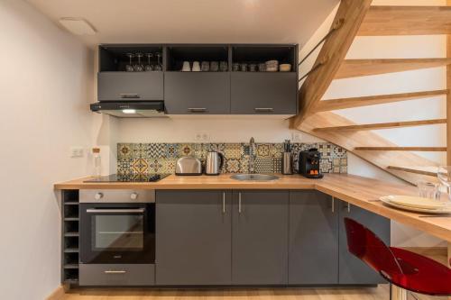 une cuisine avec des placards gris et un comptoir en bois dans l'établissement Duplex une chambre calme, proche commodités, à Lille