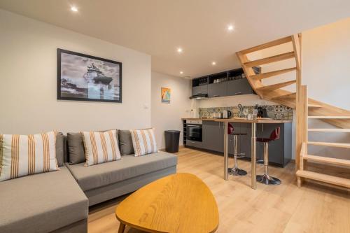 a living room with a couch and a kitchen and a staircase at Duplex une chambre calme, proche commodités in Lille