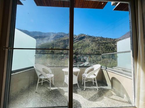 a balcony with chairs and a view of a mountain at Hotel Virasat-E-Bushahr in Rāmpur