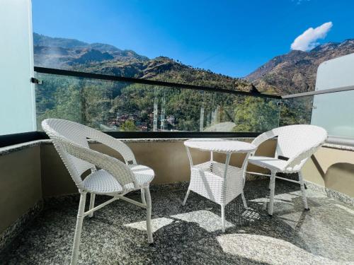 two chairs and a table on a balcony with mountains at Hotel Virasat-E-Bushahr in Rāmpur