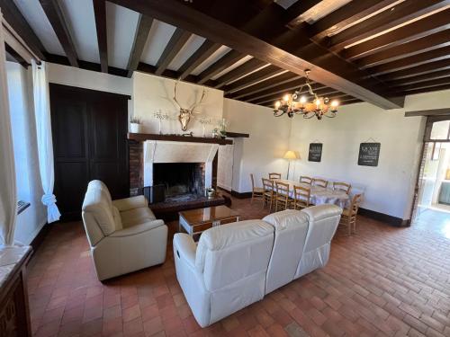 Elle comprend un salon doté d'un mobilier blanc et d'une cheminée. dans l'établissement Domaine de la Dijonniere, à Clémont