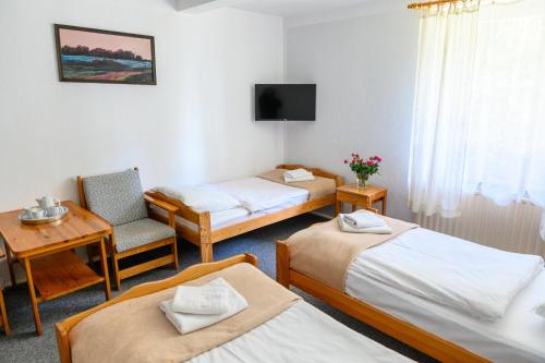 a room with three beds and a table and a chair at Kosewo 78 Family Hotel & Spa in Kosewo