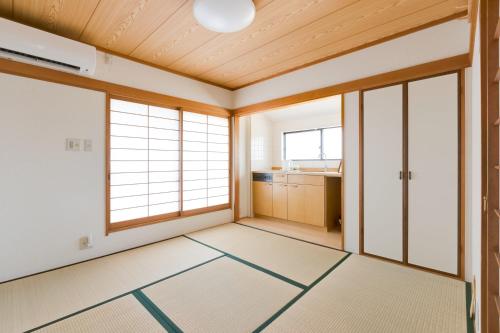 an empty room with wood ceilings and windows at PLUS 9 Station INN in Izumi-Sano