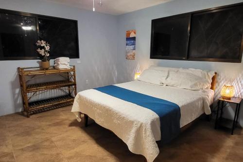 a bedroom with a bed and two large windows at Casa Garrobo in Dominical
