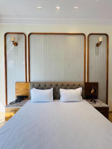 a bedroom with a large bed with two white pillows at Hotel Virasat-E-Bushahr in Rāmpur