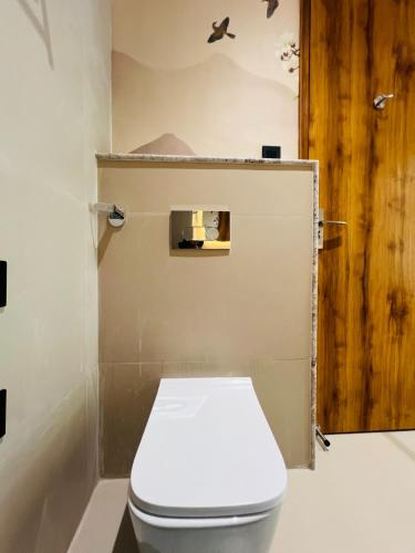 a white toilet in a bathroom with a wooden door at Hotel Virasat-E-Bushahr in Rāmpur