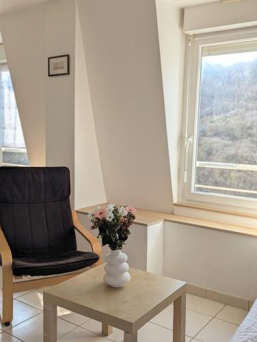 une chaise noire et un vase avec des fleurs sur une table dans l'établissement T3 vue mer - face à la plage et au sentier des douaniers, à Planguenoual