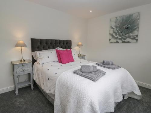 a bedroom with a large white bed with pink pillows at Yewdale View Apartment in Coniston