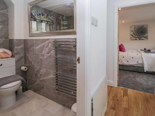 a bathroom with a toilet and a small bedroom at Yewdale View Apartment in Coniston