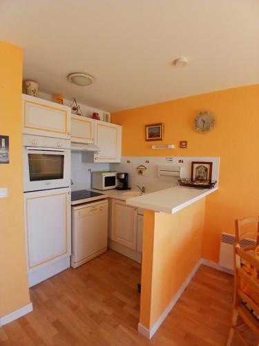 - une cuisine avec des appareils électroménagers blancs et des murs orange dans l'établissement Appar bray-dunes, à Bray-Dunes