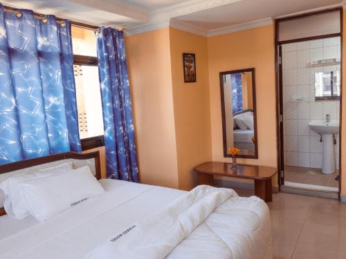 a bedroom with a bed and a sink and a mirror at Durban Hotel in Dar es Salaam