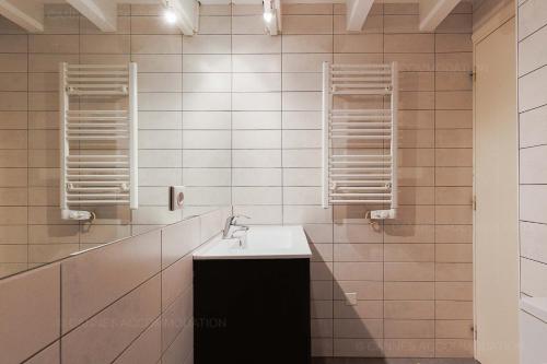 La salle de bains est pourvue de carrelage blanc, d'un lavabo et de miroirs. dans l'établissement Residence Aout 42, à Cannes