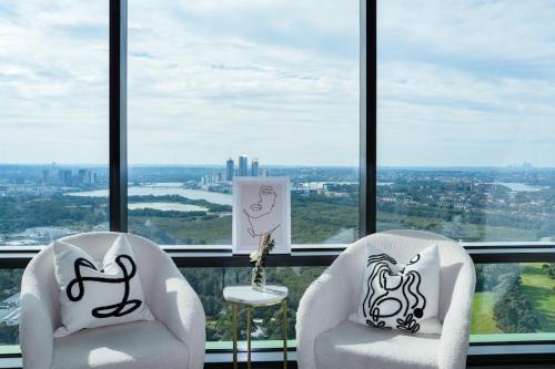 two white chairs sitting in front of a window at Skyline Retreat in Olympic Park in Sydney