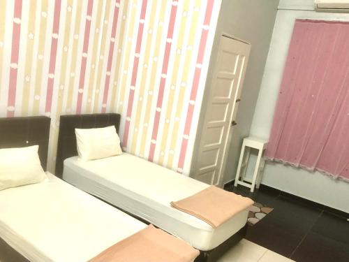 a small room with two beds and a window at Ang Rest House in Kuala Rompin