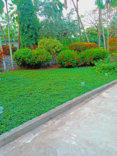 a garden with green grass and flowers and bushes at La Sagesse Hotel, Restaurant and Beach Bar in Content