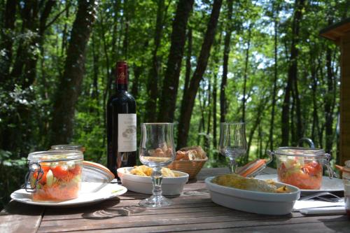 a wooden table with a bottle of wine and glasses at Cabanes de la Romaningue in Pompignac