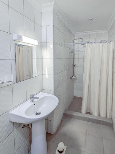 a white bathroom with a sink and a shower at Durban Hotel in Dar es Salaam