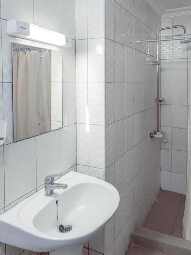 a white bathroom with a sink and a mirror at Durban Hotel in Dar es Salaam