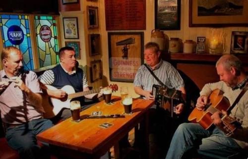 a group of men sitting around a table playing guitar at Nellie's Village Stay in Beaufort