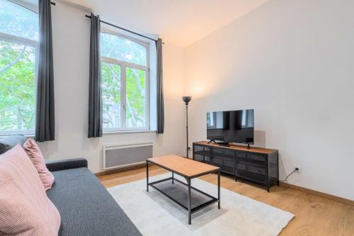 un salon avec un canapé, une télévision et une table dans l'établissement Lille Centre - Appartement Lumineux !, à Lille