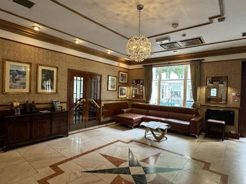 a large living room with a couch and a chandelier at Berjaya Eden Park London Hotel in London
