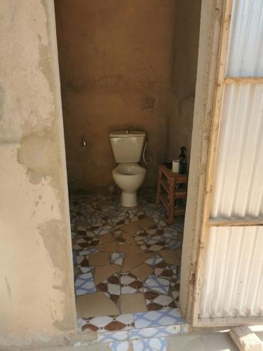 a bathroom with a toilet and a tiled floor at Les jardins fleuris de lompoul sur mer in Tioukougne Peul