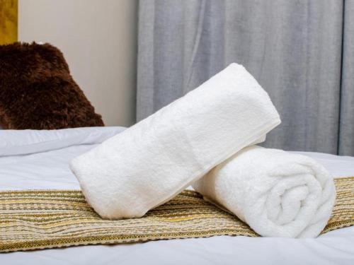 a roll of white towels on top of a bed at Comfort on Wrench in Cape Town