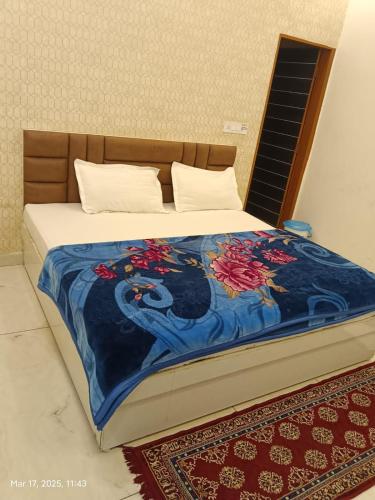 a bed with a blue blanket with flowers on it at Mahima hotel in Samālkha