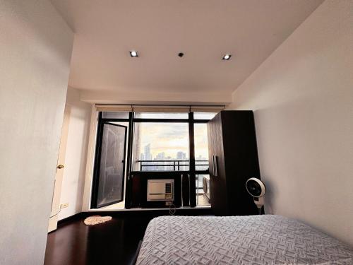 a bedroom with a bed and a large window at The Gramercy Residences NEW Sleek 1BR Suite, 600mbps Wifi, Netflix & FREE Amenities in Manila