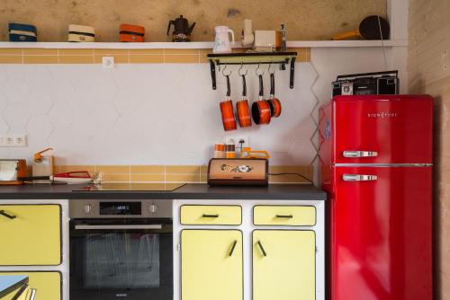 une cuisine avec un réfrigérateur rouge et des armoires jaunes dans l'établissement So Vintage - Gite seventies en Anjou, à Sermaise