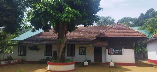 a building with a tree in front of it at Akkara Homestay in Kottayam