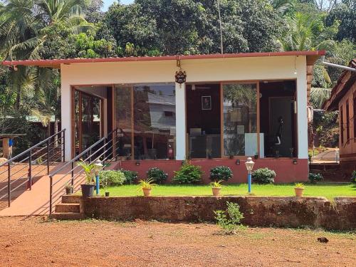 a house with a front porch with plants in the yard at West Coast Gokarna in Gokarna