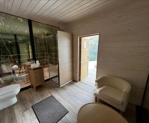 a bathroom with a toilet and a chair at Cabanes de la Romaningue in Pompignac