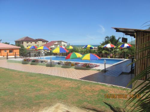 a swimming pool with colorful umbrellas and a pool at Jamaica Inn Guest House in Bortianor