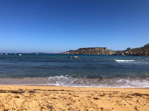 a sandy beach with boats in the water at Sunny Penthouse Central in Mosta