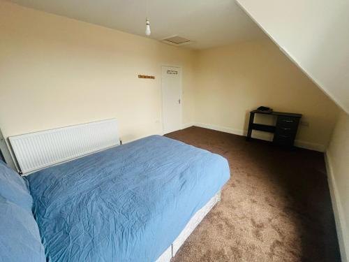 a bedroom with a blue bed and a black table at Double Room Near Railway station & Football Ground 88 in Nottingham