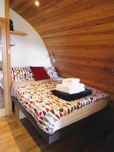 a bed in a room with a wooden wall at Harlosh Hideaways - Stargazer Pod in Harlosh