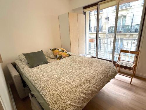 une chambre avec un lit et une grande fenêtre dans l'établissement L'appartement Larminat, à Paris