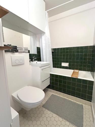 La salle de bains est pourvue de toilettes et d'un mur carrelé vert. dans l'établissement L'appartement Larminat, à Paris