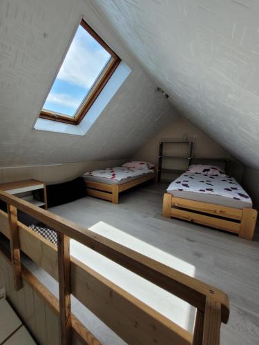 a attic room with two beds and a window at Domki Eridan nad morzem in Wisełka