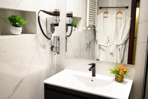 een witte badkamer met een wastafel en een spiegel bij Park Hotel Plovdiv in Plovdiv