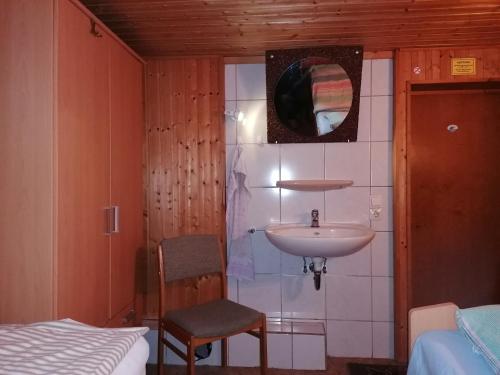 a bathroom with a sink and a chair and a bed at Haus am Waldrand in Freital