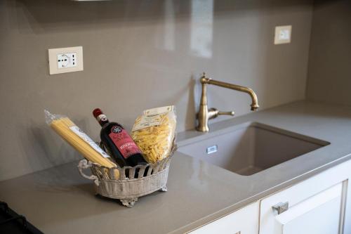a basket with bottles of wine on a counter next to a sink at Lajatico Rentals -Grotticella House, SPA Apartment in Peccioli in Peccioli