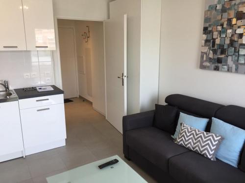 un salon avec un canapé noir et une cuisine dans l'établissement Ma place au sud Nice 604, à Nice