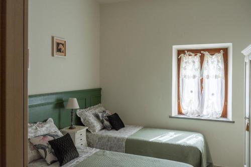 a bedroom with two beds and a window at Lajatico Rentals -Grotticella House, SPA Apartment in Peccioli in Peccioli